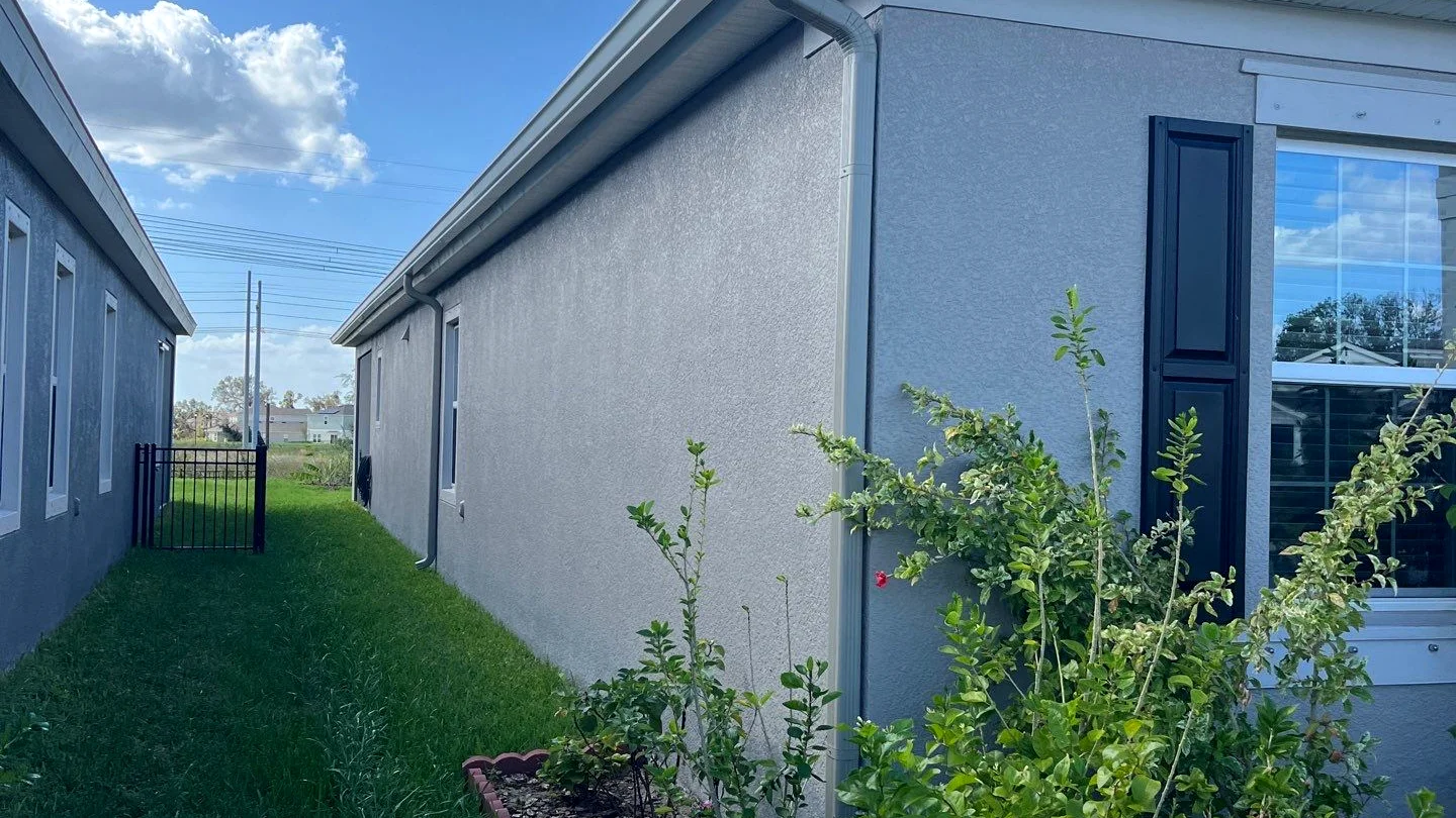 Single-story ranch with new gutters draining toward underground piping in Orlando